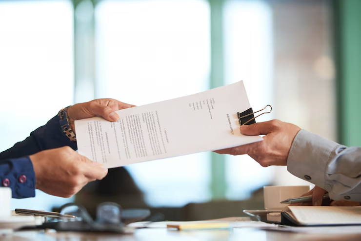 A person handing over a document to another person