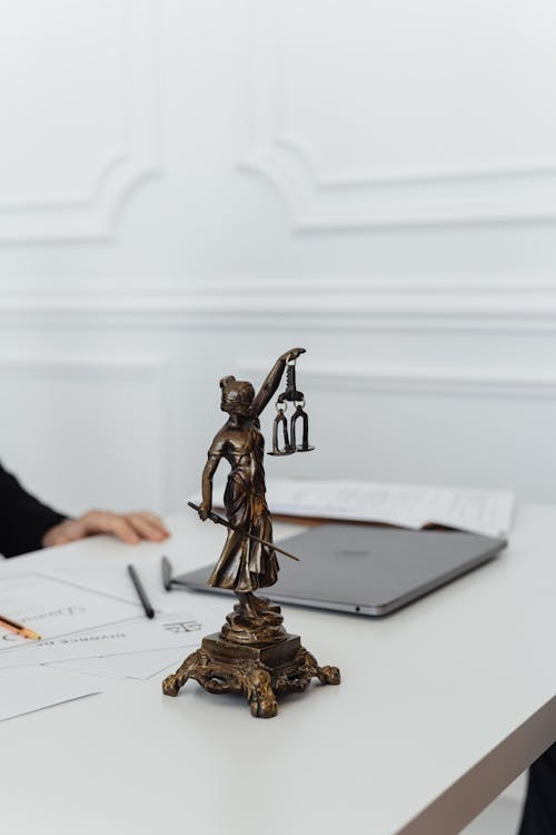 A close-up of a Lady Justice figurine on a white table.