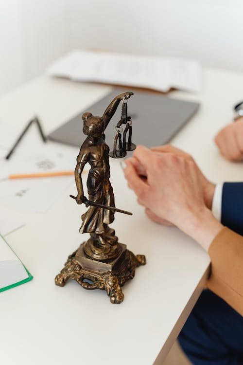 A close-up of a bronze Lady Justice figurine on a white table.