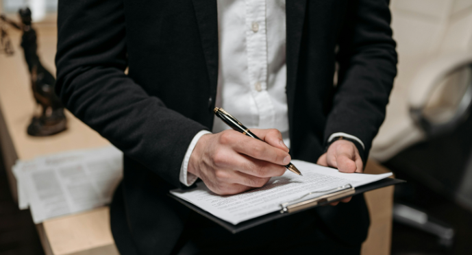 A close-up of a person holding a clipboard with papers attached.