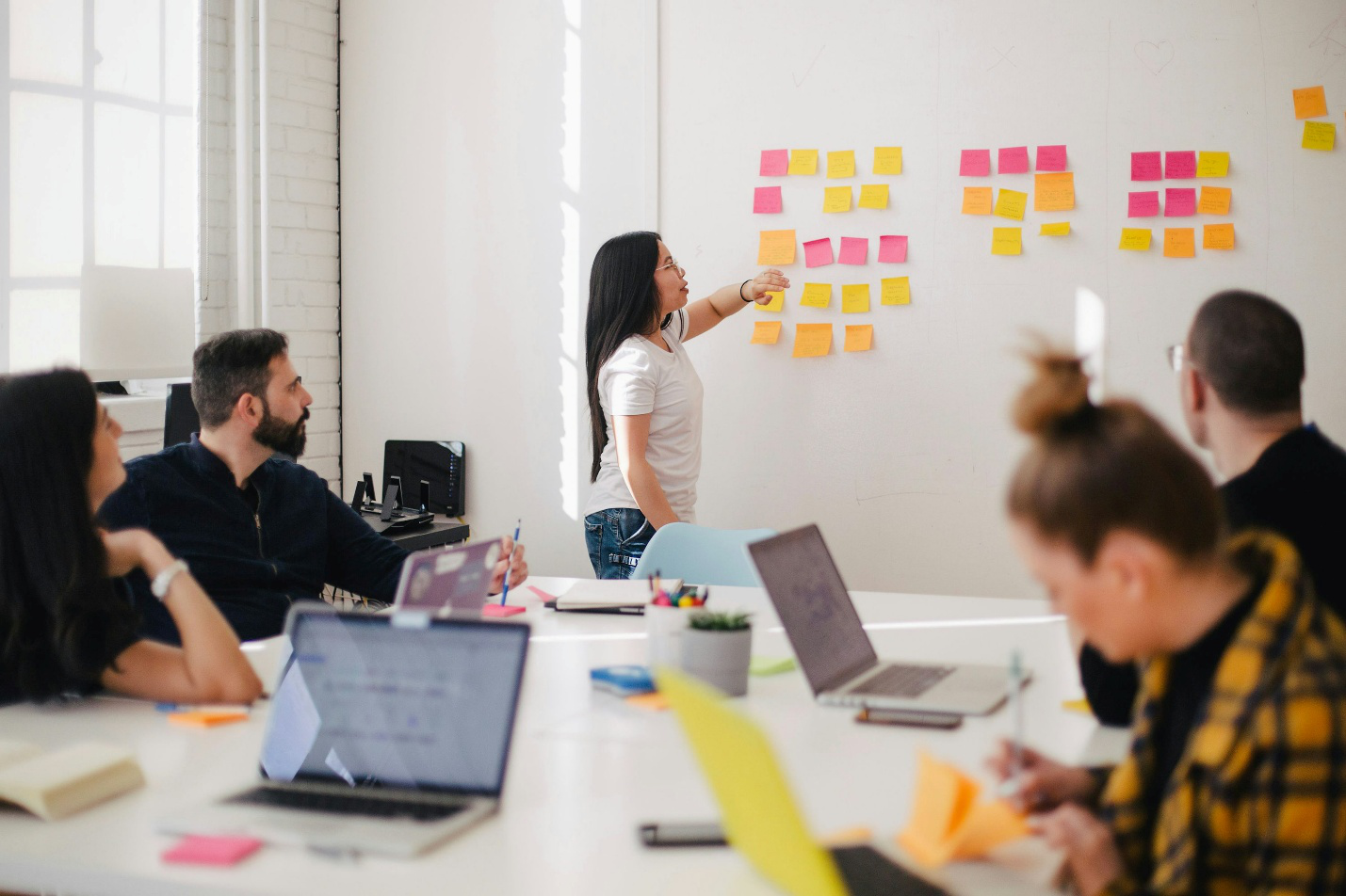 A group of people in a meeting with sticky notes on a wall