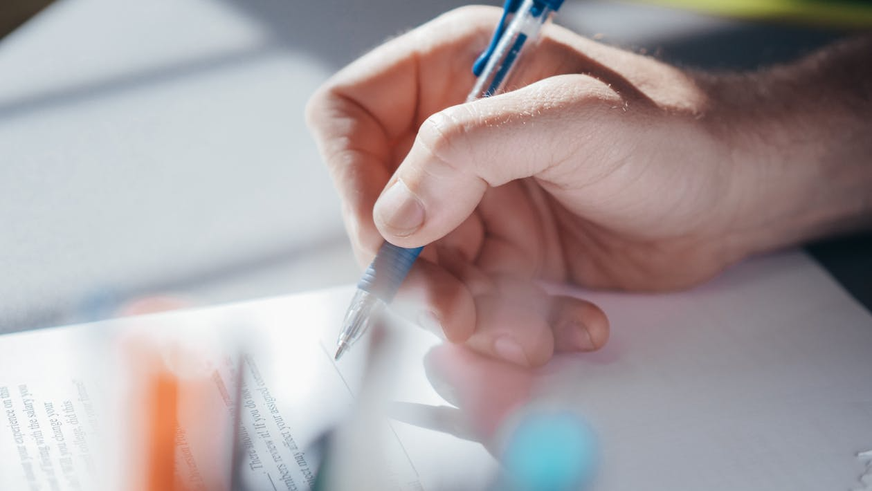 A person holding a pen while preparing to write on paper.