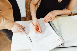 A woman in a black sleeveless dress writing notes on paper.
