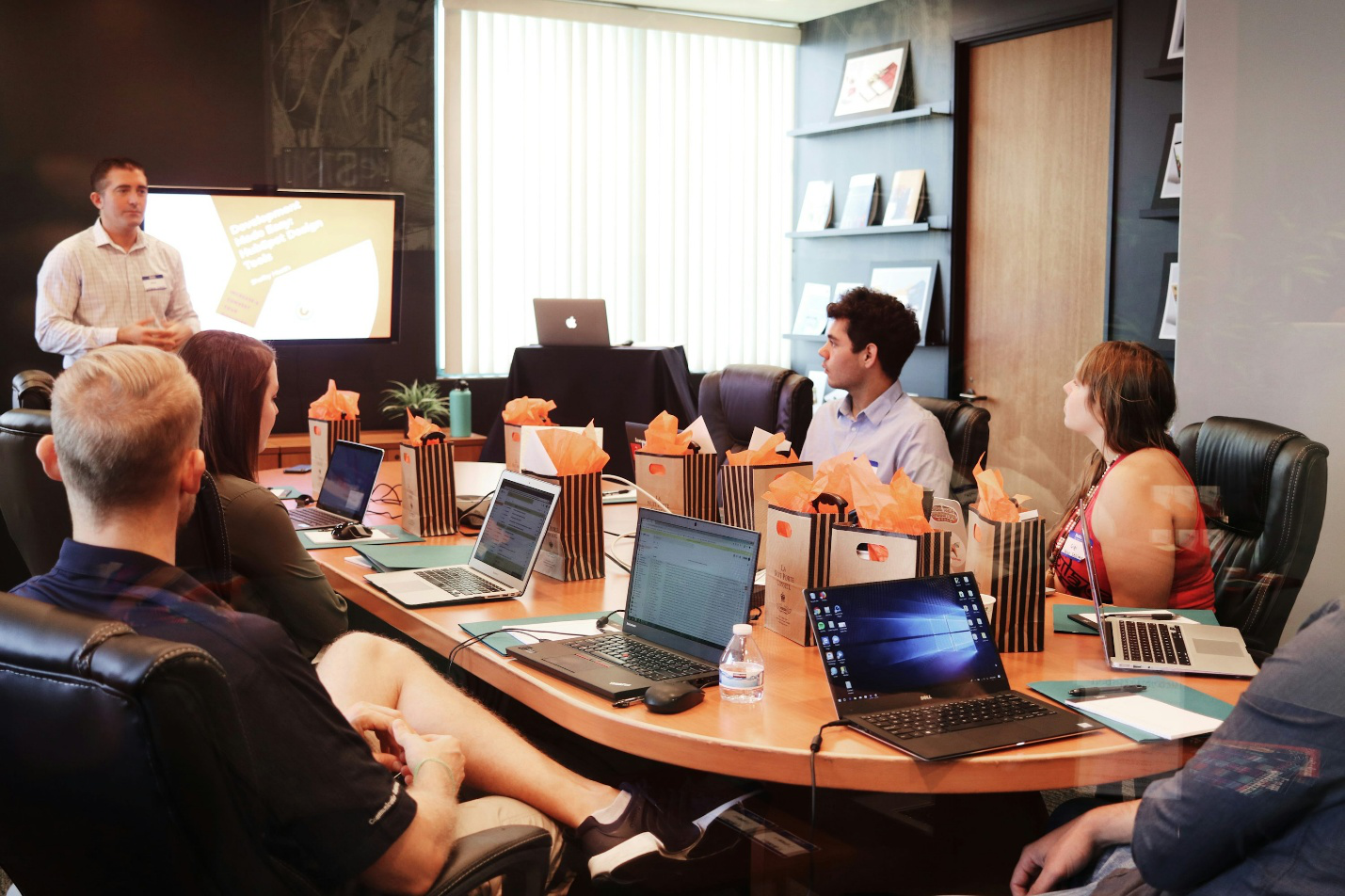 People sitting at a table with their laptops in a meeting