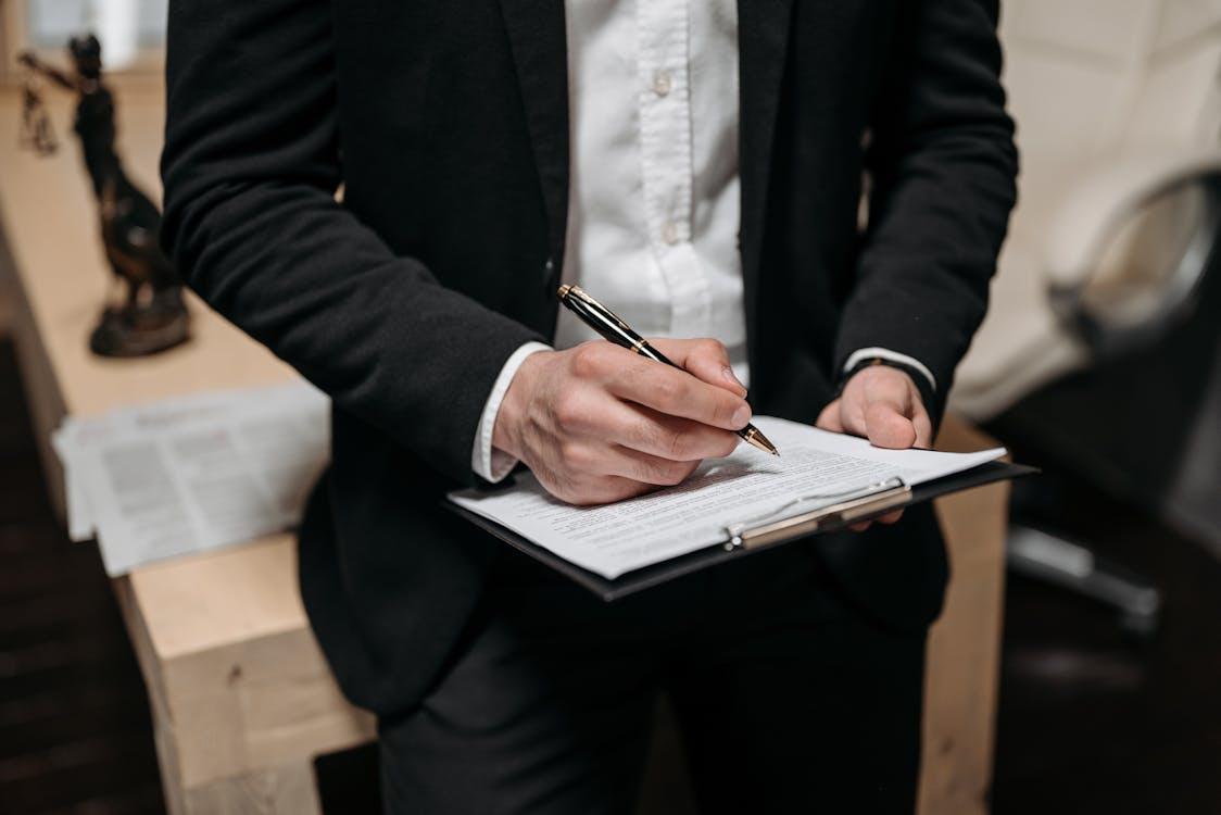 Person holding a clipboard with contract paperwork.