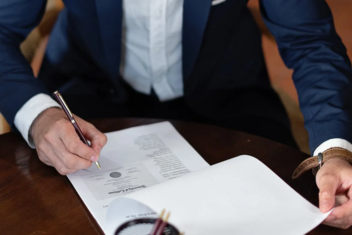 Man in a suit signing formal documents.