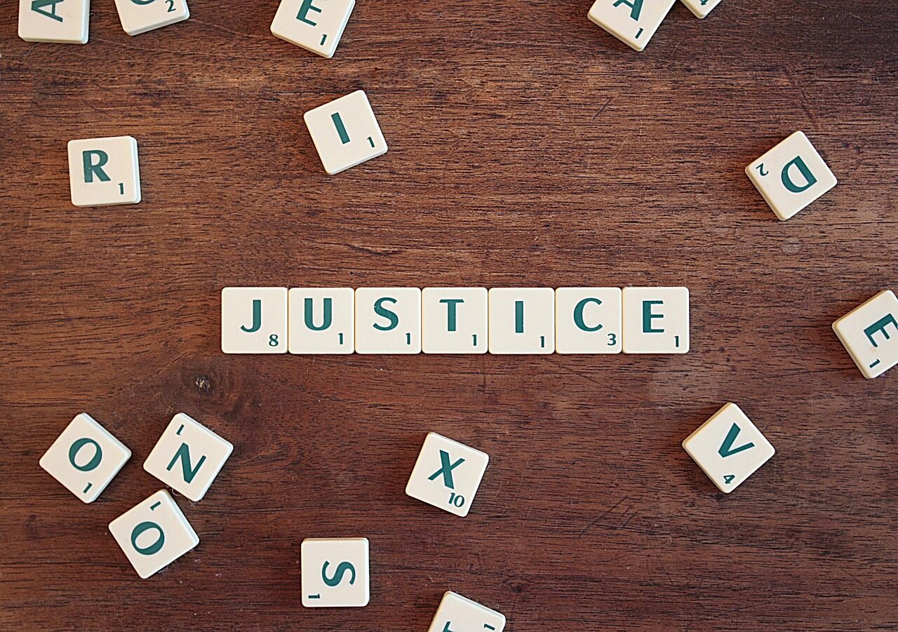 Scrabble tiles make up the word “Justice”