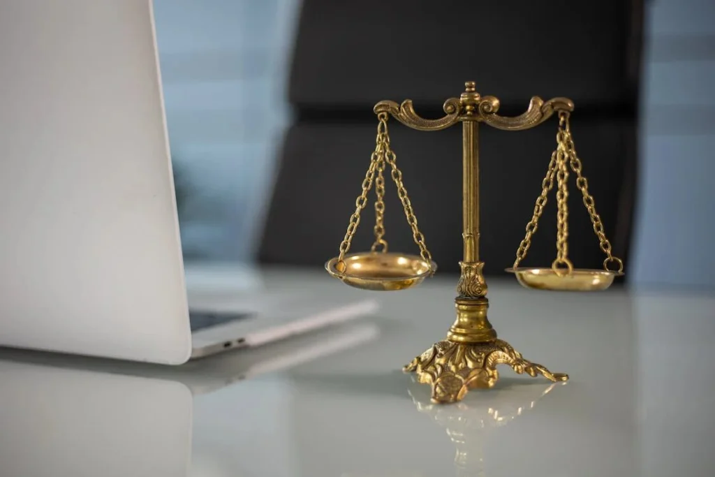 A golden balance scale next to a laptop