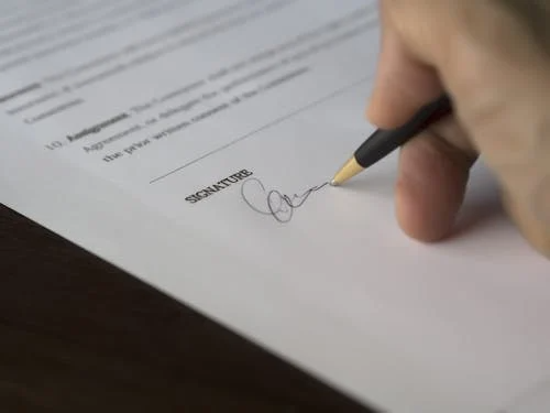 A close-up of a person signing a document