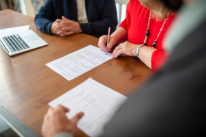A woman in red clothes signing a contract in an office