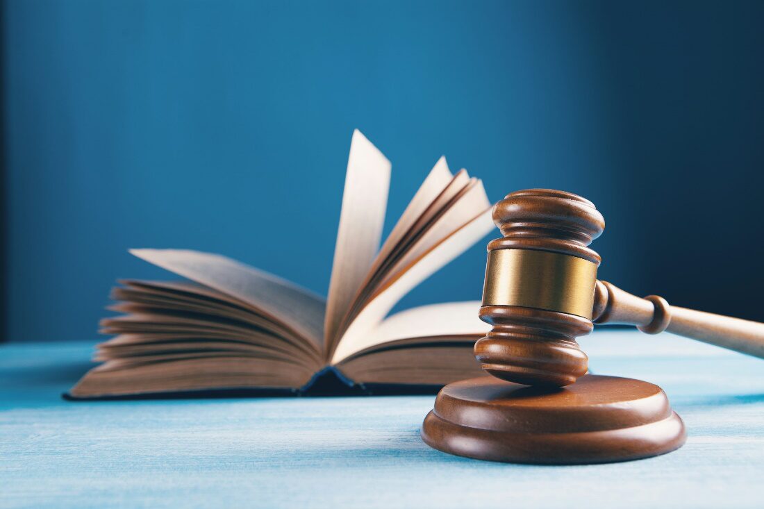 A wooden gavel and a book on a blue surface