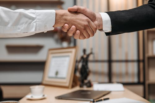 Two people shaking hands over a table in a lawyer’s office