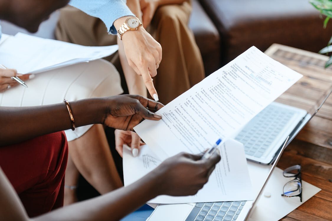 A person holding papers in front of a laptop