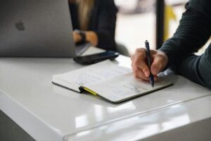Business professional taking handwritten notes during a commercial litigation planning meeting