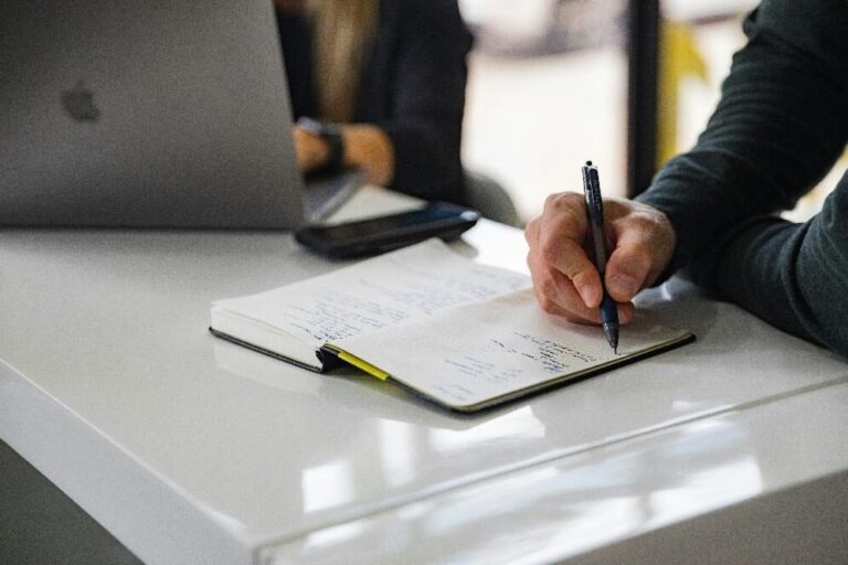 Business professional taking handwritten notes during a commercial litigation planning meeting