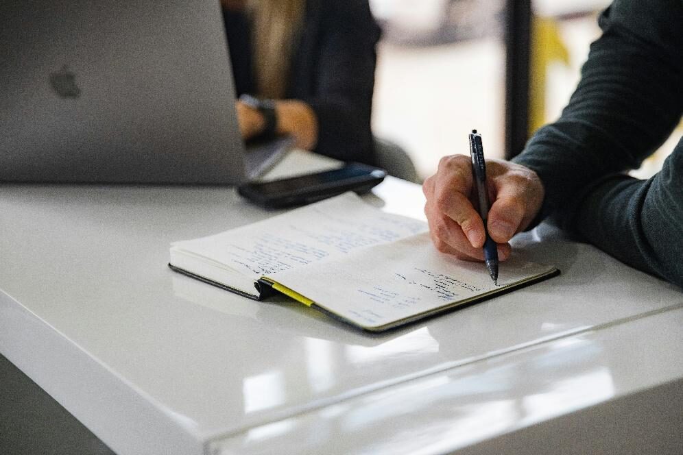 Business professional taking handwritten notes during a commercial litigation planning meeting
