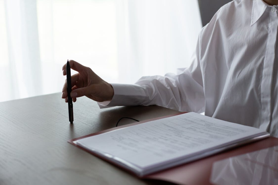 A person holding a pen and checking papers on a table