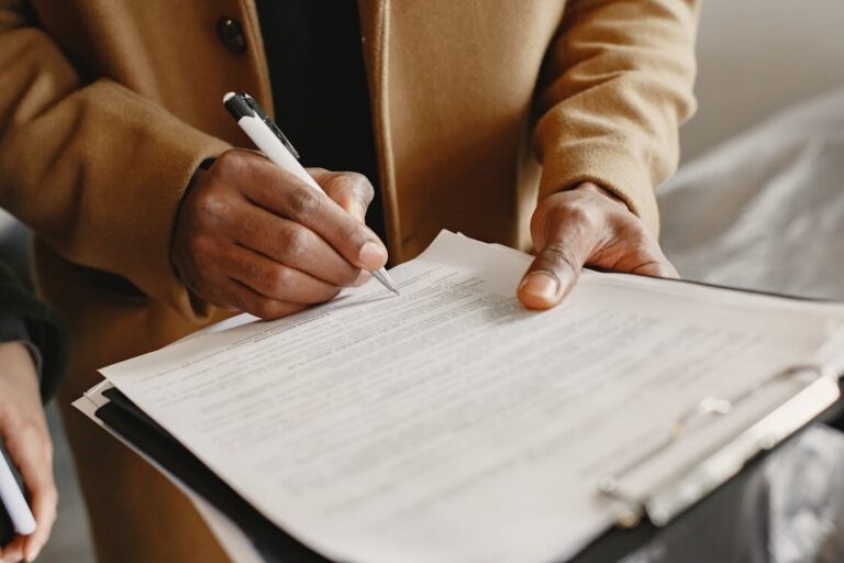A person signing a paper attached to a clipboard