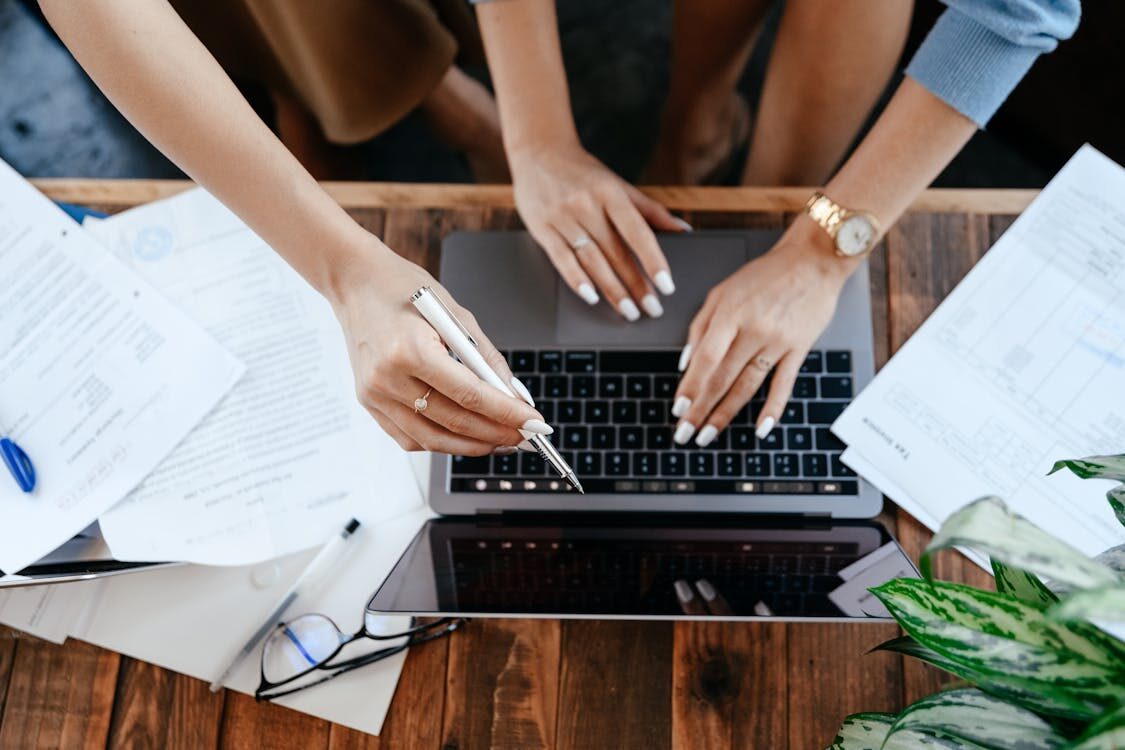 A group of people pointing to a laptop
