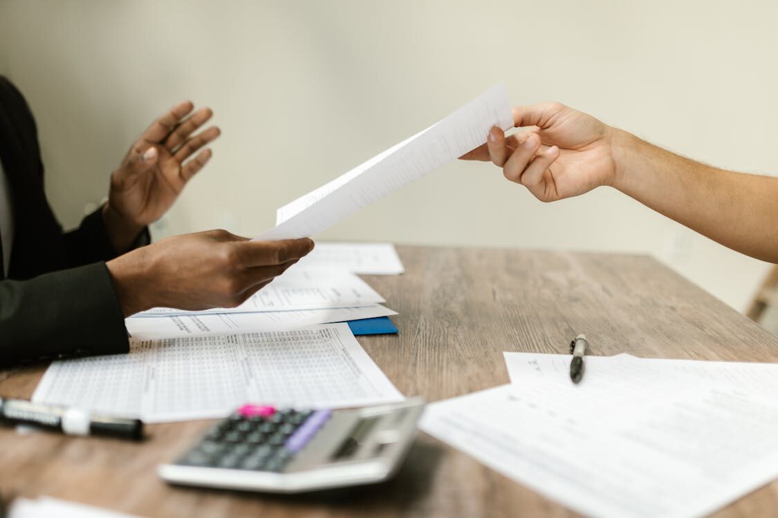A person passing a document to another person