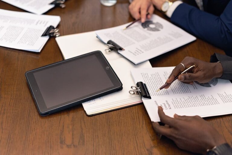 Two people reviewing documents with a tablet in the background