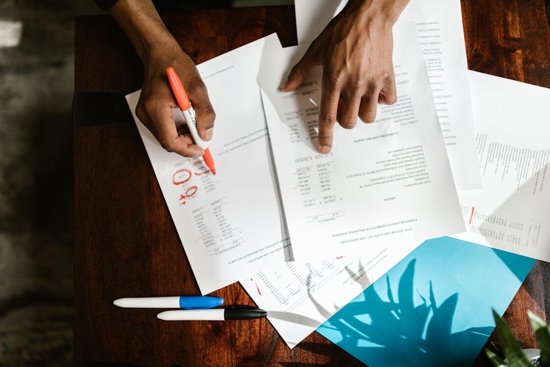 A person writing on a document with a marker