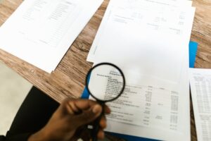 A person using a magnifying glass on documents