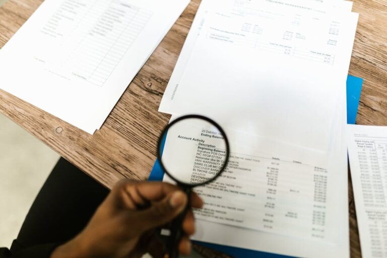 A person using a magnifying glass on documents