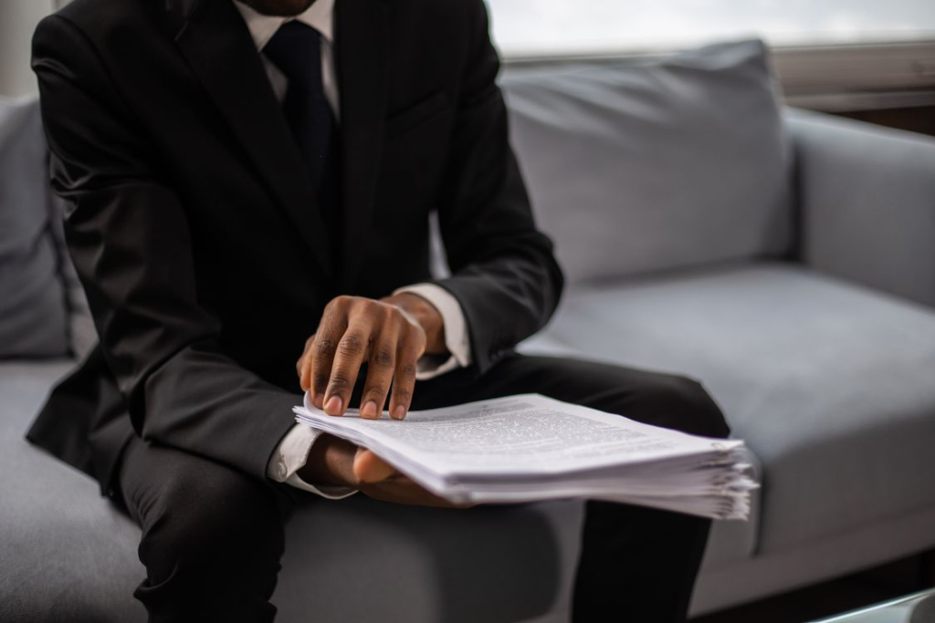 A person holding a document while sitting on the couch