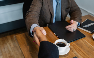Two people shaking hands over a file on the table