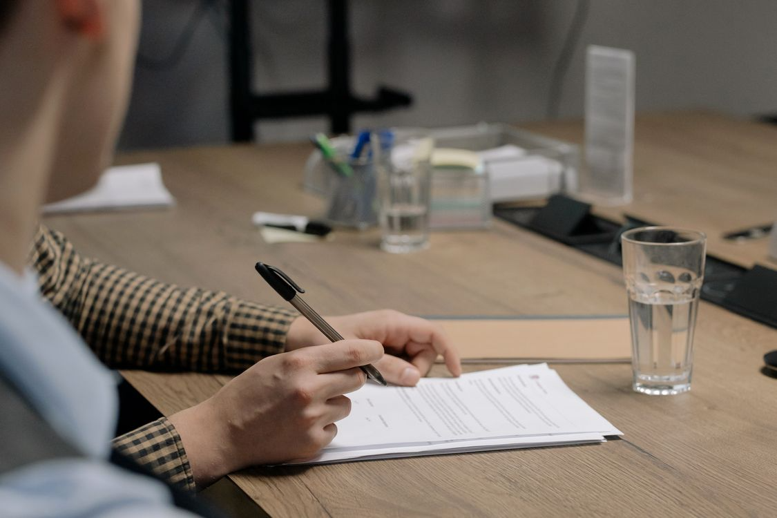 A person signing documents on the table