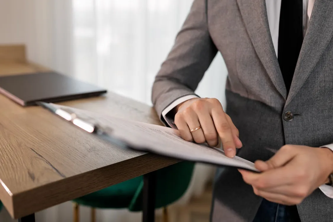 Business professional examining a document at a desk while reviewing contract paperwork
