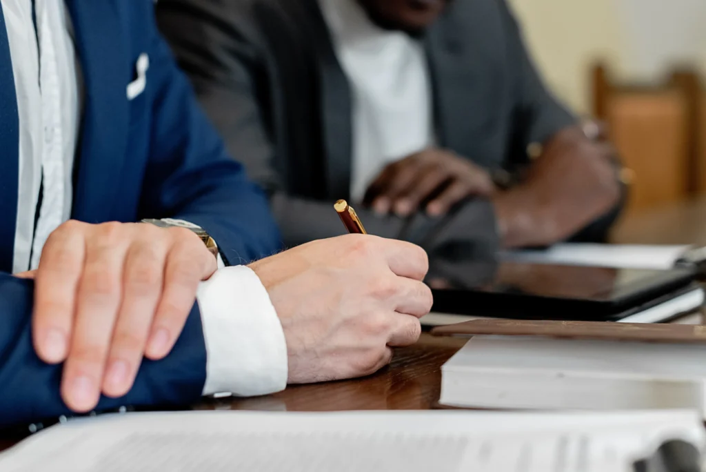 Two businessmen sitting at a conference table reviewing confidential corporate documents and financial records.