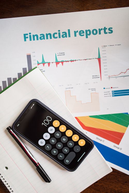 An office table with a desktop calculator placed on top of financial documents and transaction worksheets.