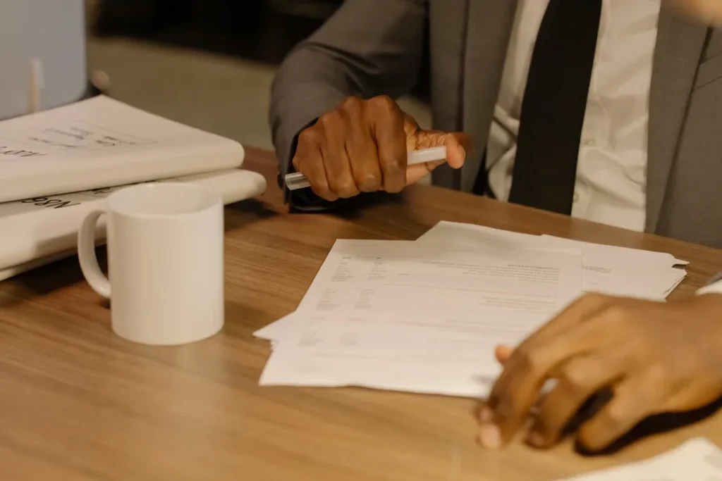 Business professional holding a pen while examining paperwork during a contract review