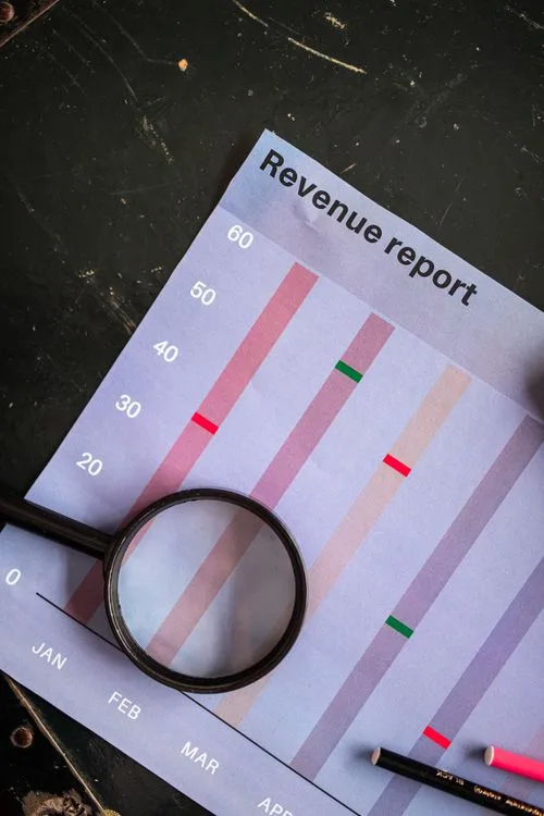 A magnifying glass zooming in on a printed financial graph paper during an audit review.