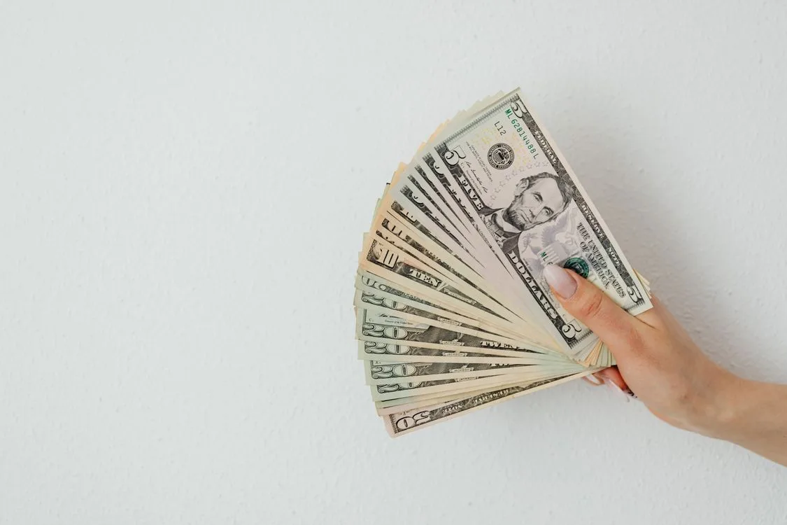 A person holding money on a white surface