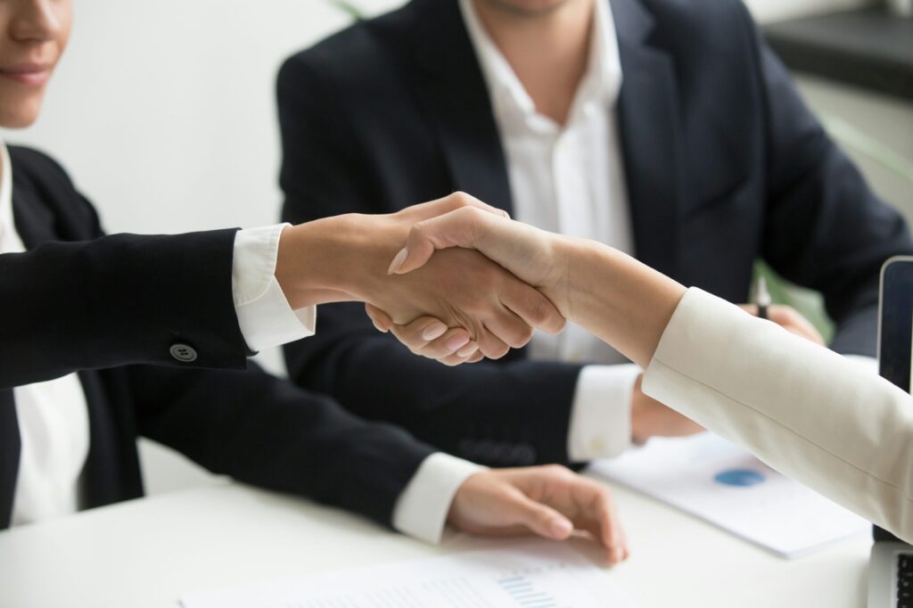 Two people shake hands during a meeting