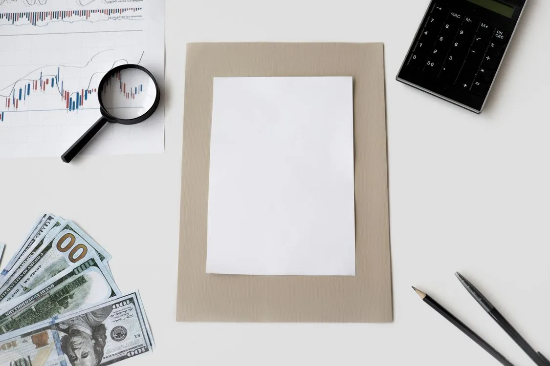 A white paper, financial report, calculator, and currency placed on the table