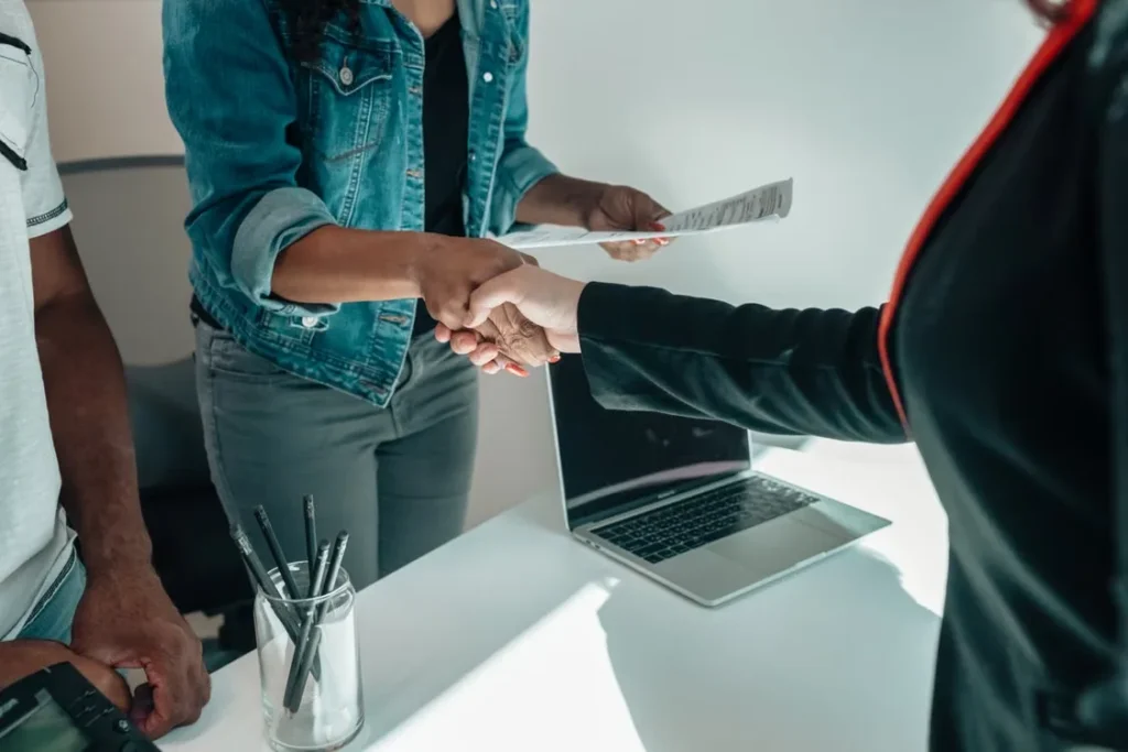 A person holding a paper and shaking hands with another person