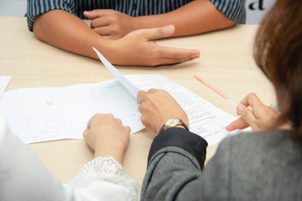 Three people reviewing documents at a meeting table