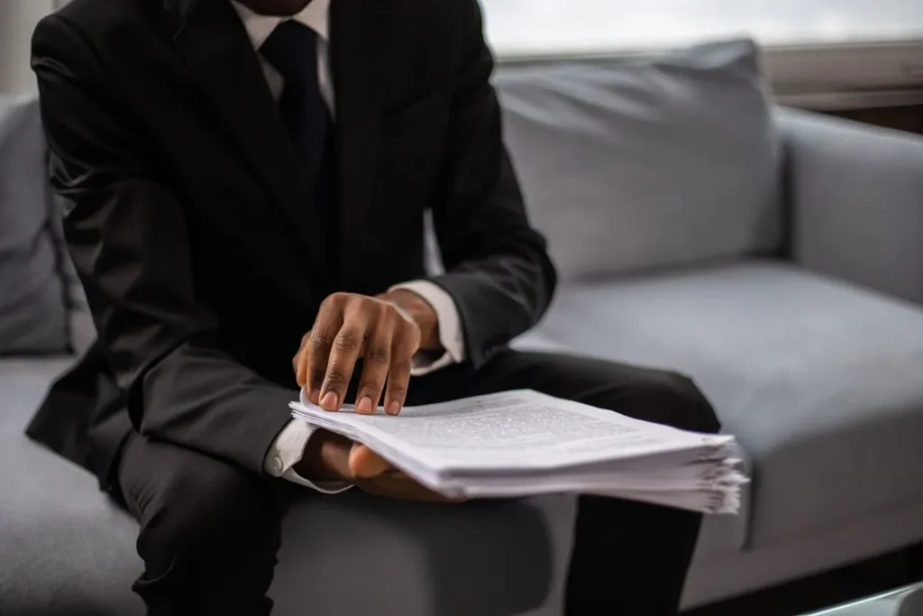 A person holding a document while sitting on the couch