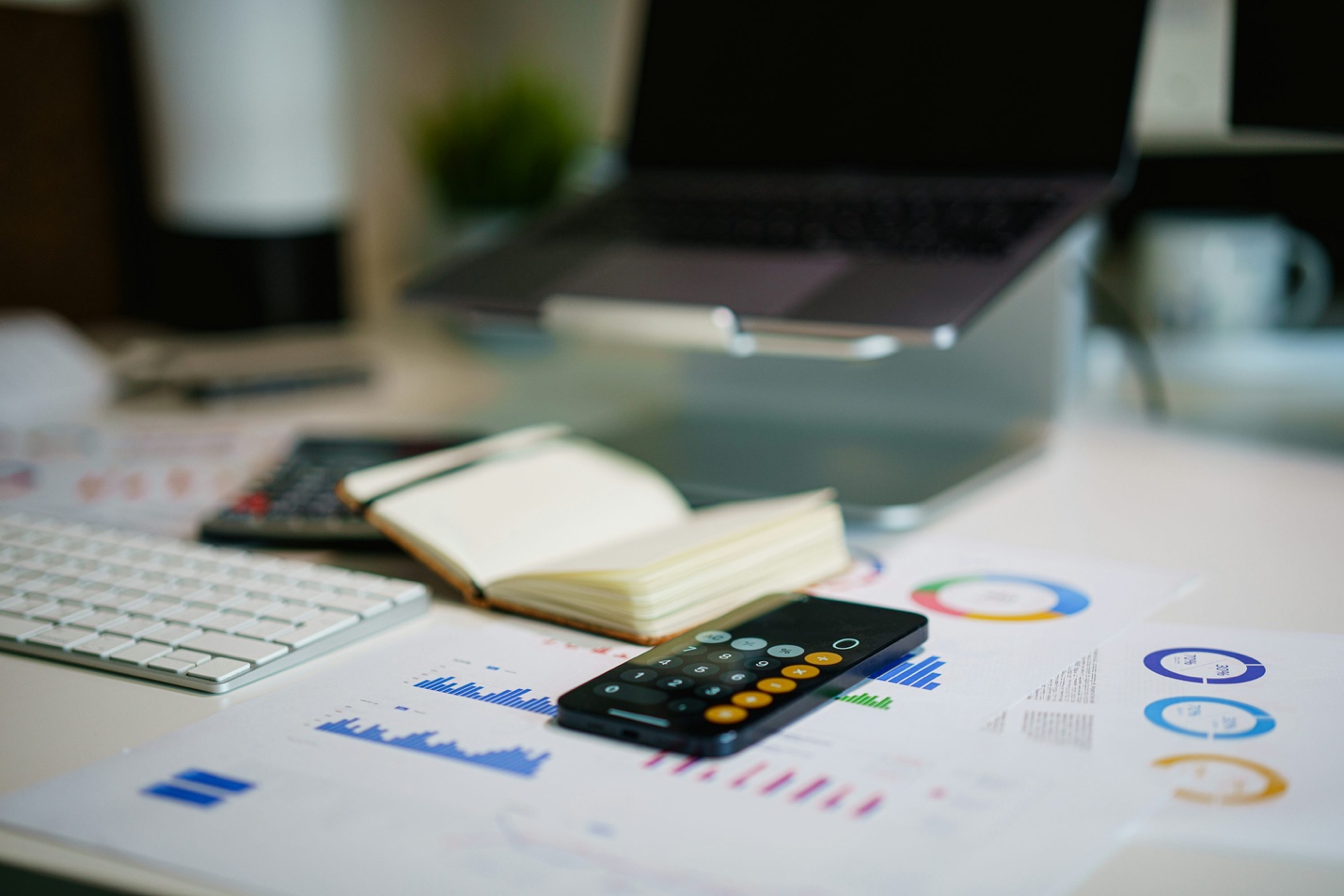A desk with laptop, calculators, and financial charts