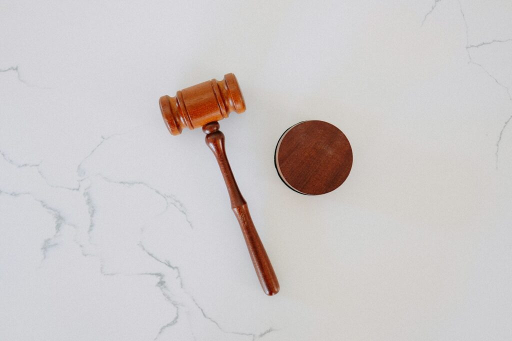 A wooden legal gavel resting on a round sound block atop a light marble surface.