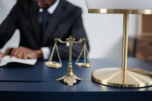 A brass scale of justice standing on a polished wooden desk in a law office.